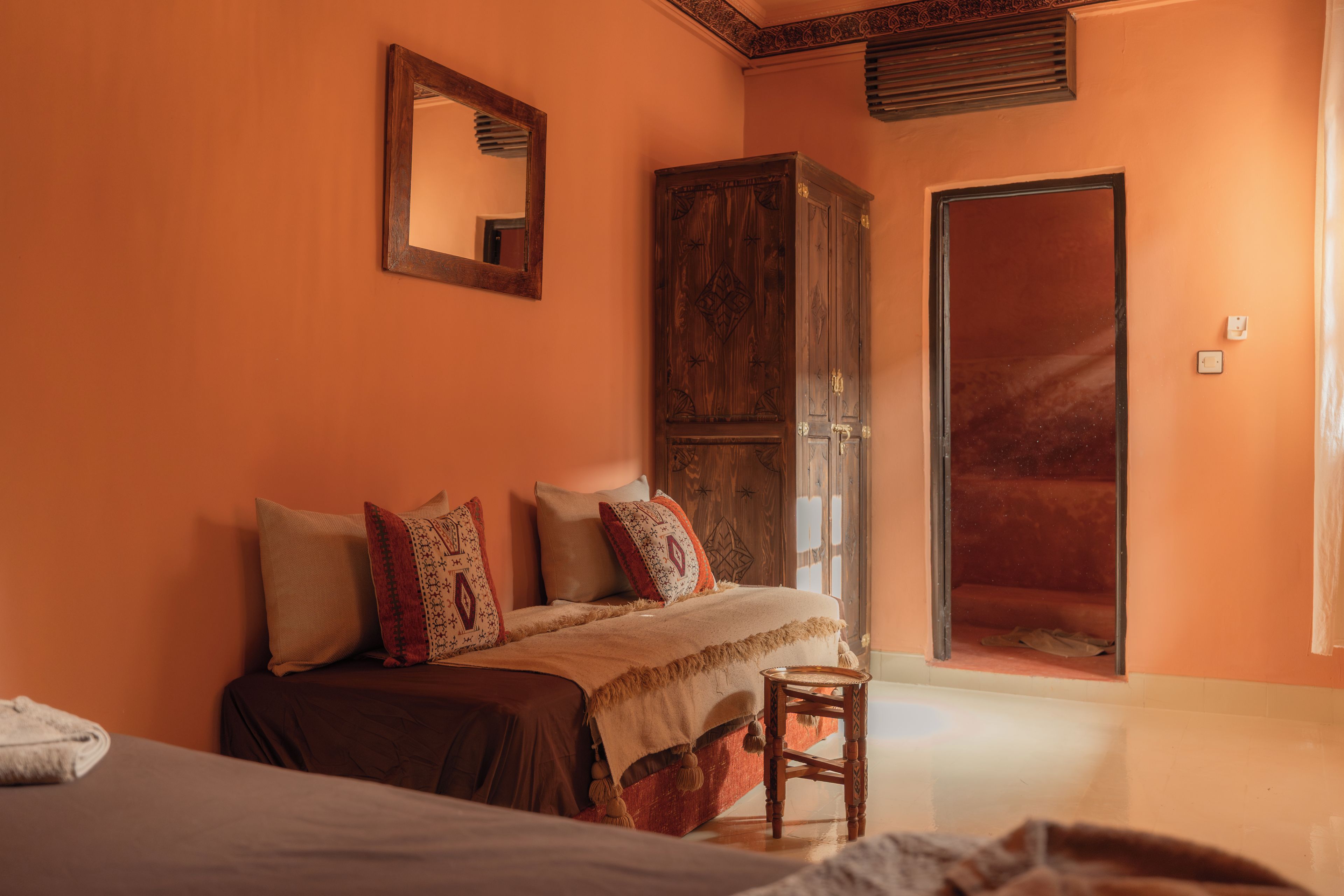 Een slaapkamer met een bed, een houten garderobe, een spiegel en een deur.