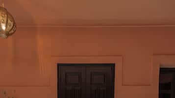 Una puerta doble cerrada con manija de bronce, sobre un muro color melocotón.