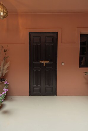 A closed double door with a brass handle, set against a peach-colored wall. - Riad Hima by Assila (Marrakech)