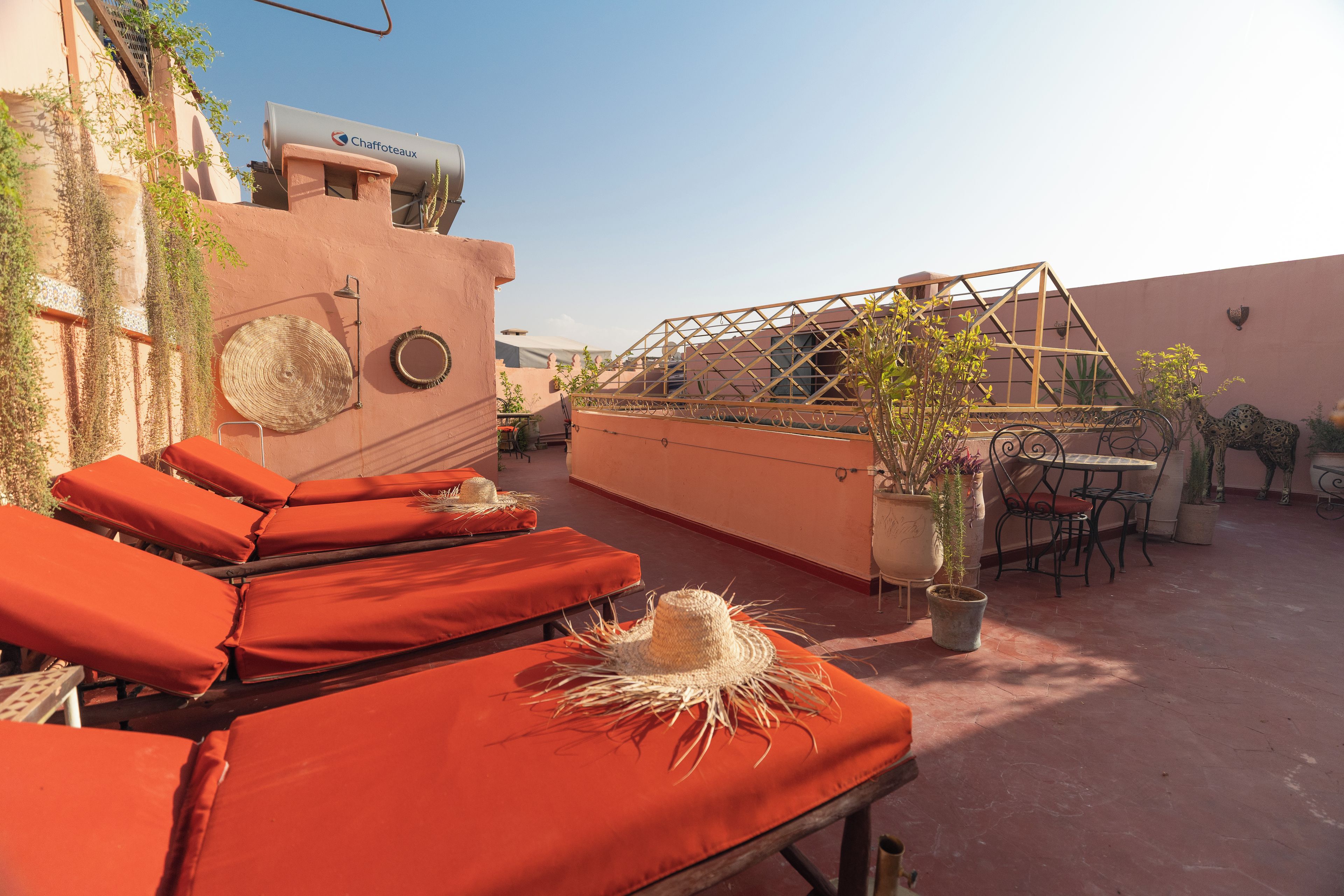Una terraza en la azotea con sillones de descanso, una fuente de agua y una pérgola.