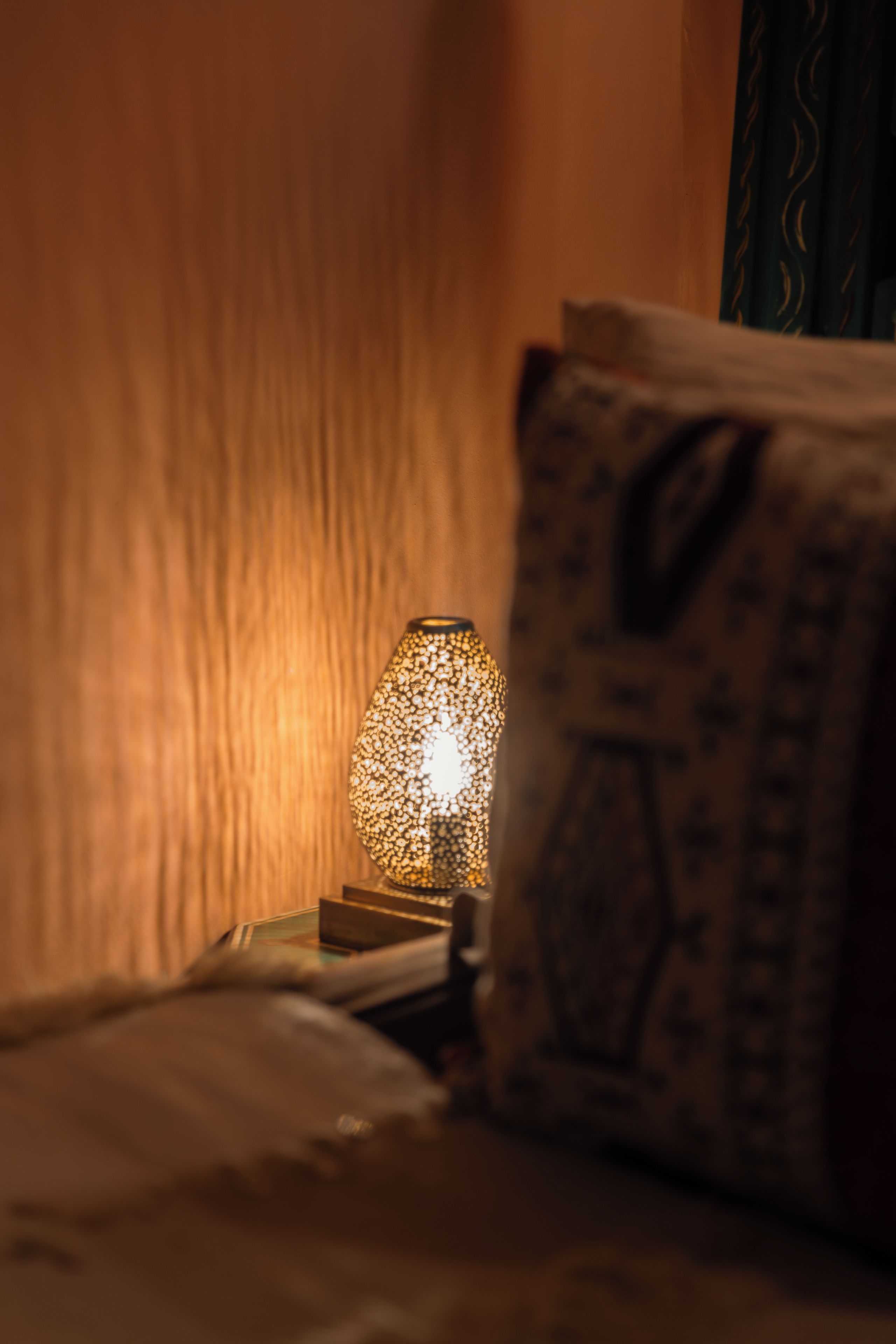 A bed with a pillow and a lamp on a bedside table.