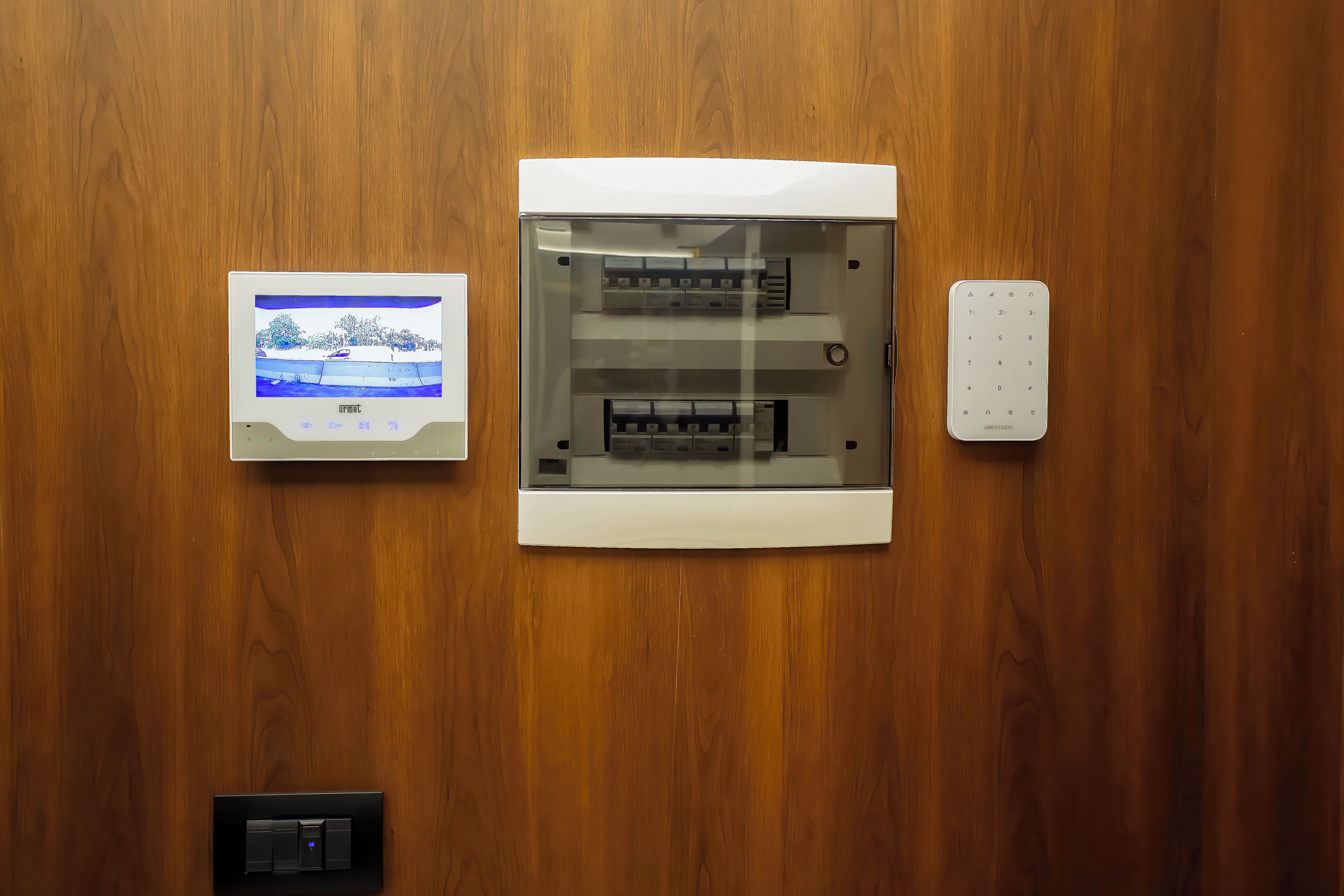 Un thermostat fixé au mur, une horloge numérique et une prise de courant sur un mur en bois.