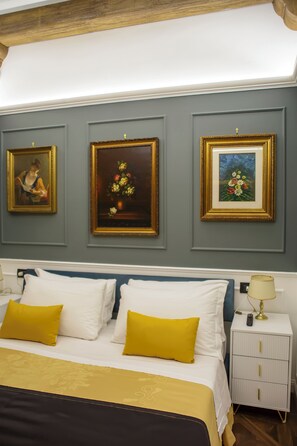 Una habitación de hotel con una cama, una mesita de noche y tres cuadros en la pared.