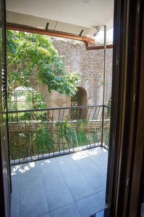 Un balcón con vistas a una pared de piedra y follaje.