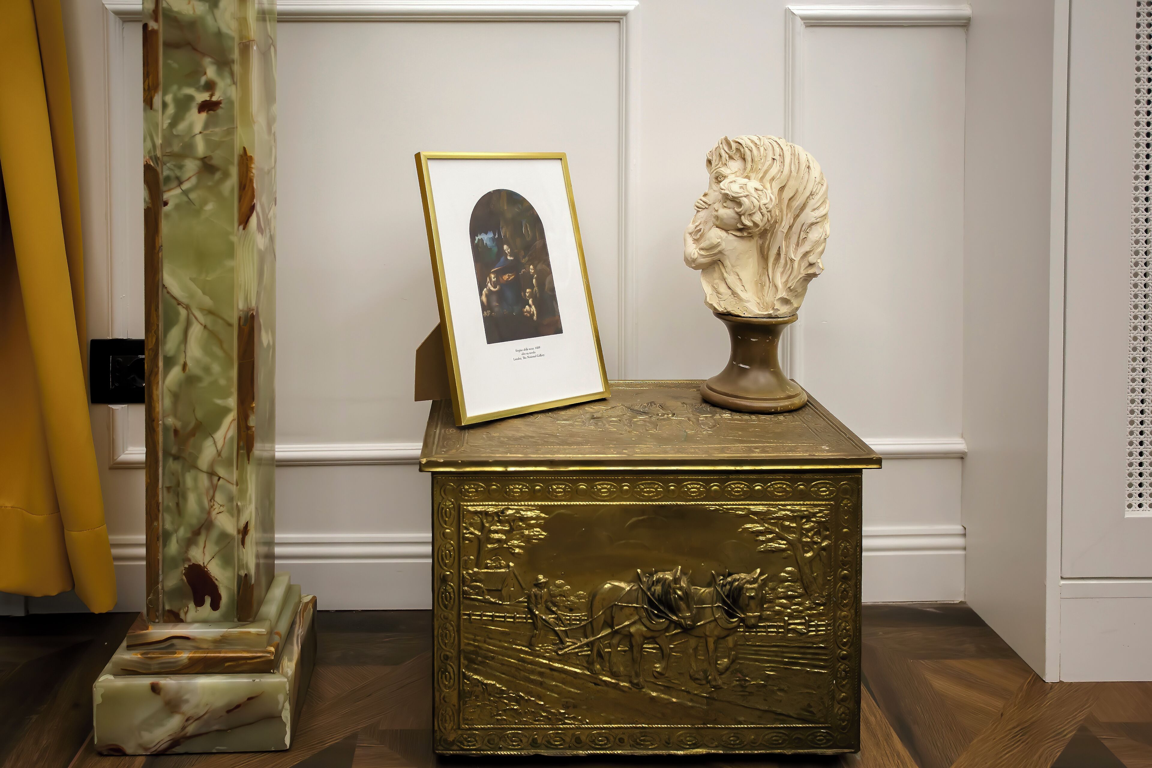 A decorative brass box with a relief sculpture and a framed picture.
