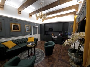 Una sala de estar moderna con un sofá modular, una mesita redonda y un sillón verde.