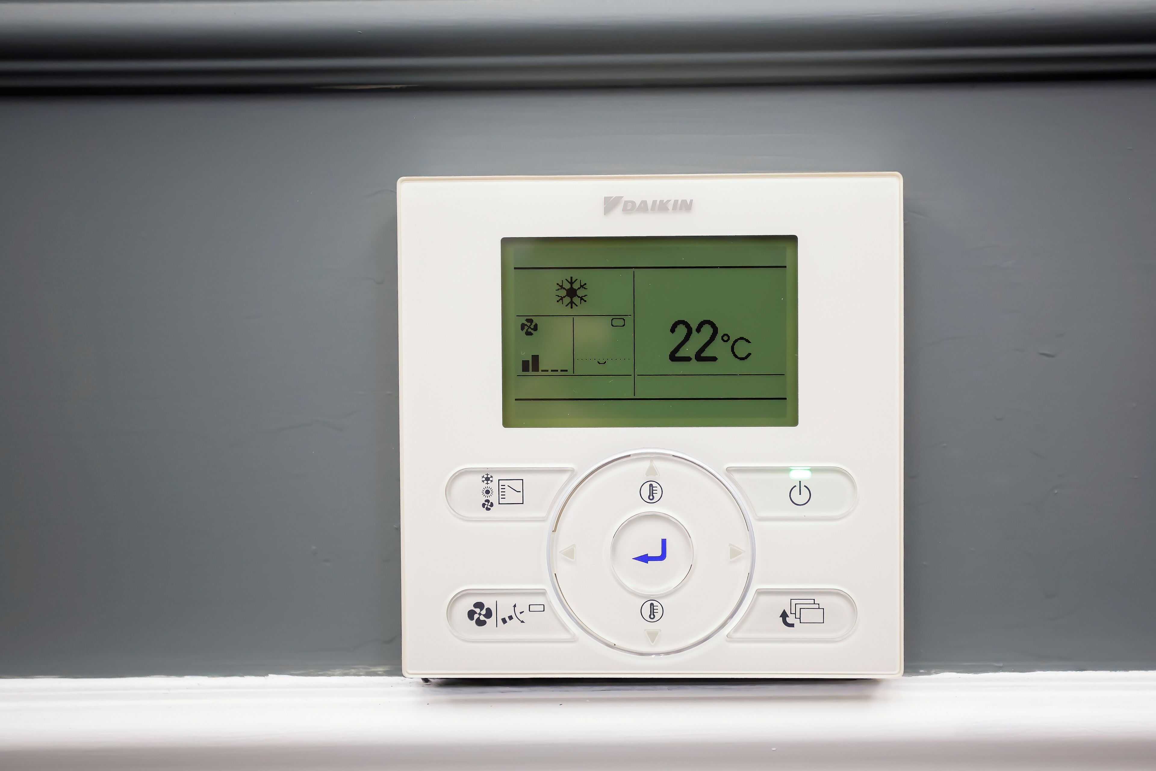 Termòstat amb pantalla digital que mostra 22°C, botons de control i el nom de la marca 'DAIKIN'.
