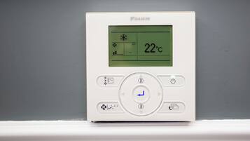 Termòstat amb pantalla digital que mostra 22°C, botons de control i el nom de la marca 'DAIKIN'.