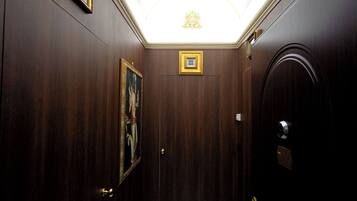 A hallway with a marble floor, wooden walls, a framed picture, and a ceiling light.