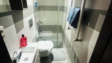 Un baño pequeño con inodoro, lavabo y ducha.