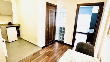 Una cocina moderna con refrigerador empotrado, un comedor con mesa de mármol y piso de madera.