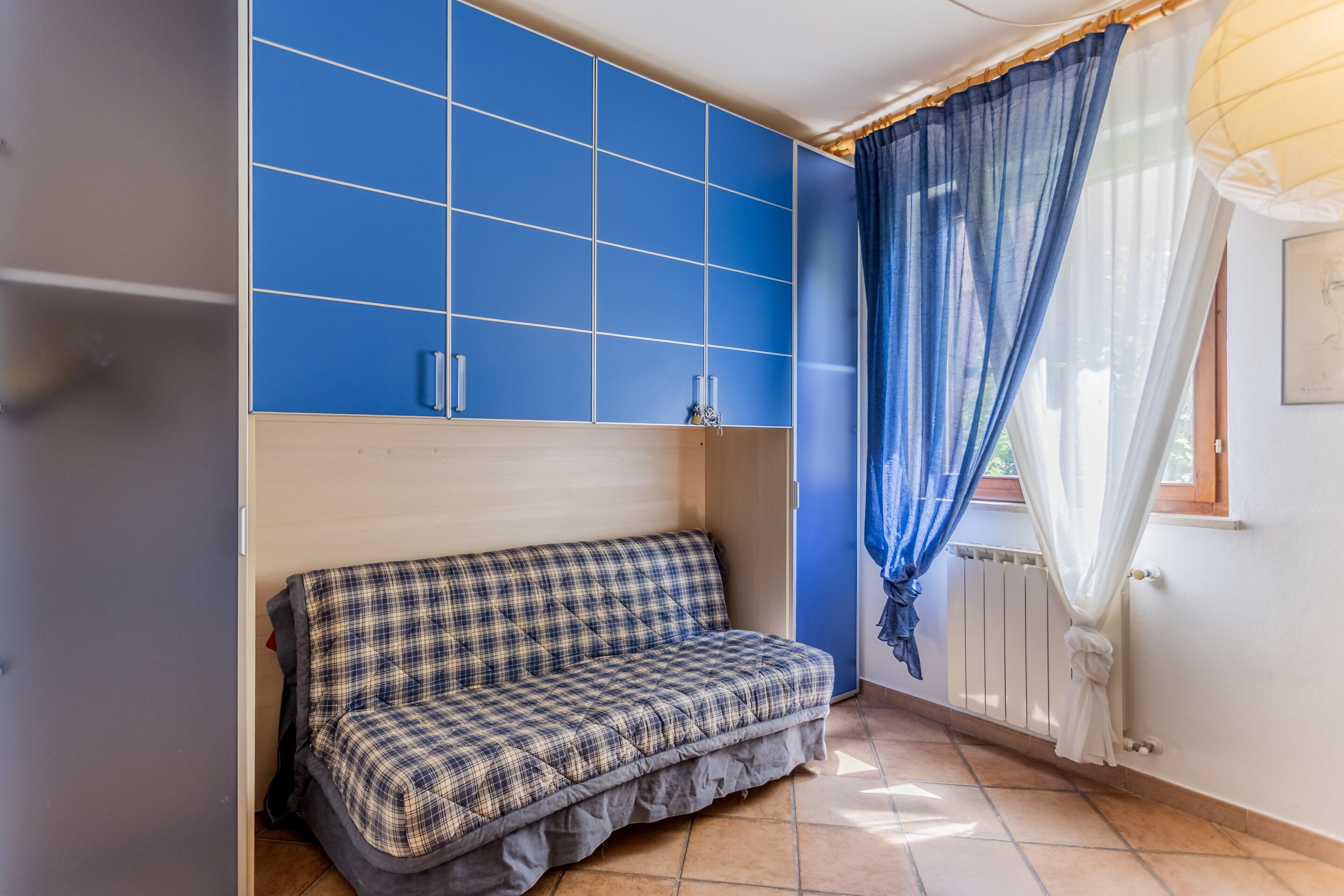 Une pièce avec un mur bleu, un canapé et une fenêtre avec des rideaux.