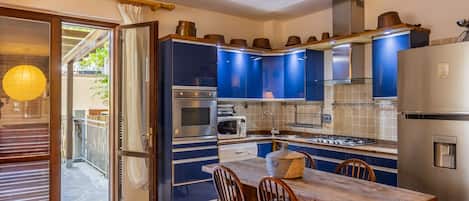 A compact kitchen with built-in appliances, a dining table with chairs, and a sliding glass door leading to an outdoor area.