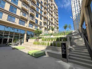 Ein modernes Gebäude mit mehreren Balkonen, einer Treppe und Außenbereichen mit Sitzgelegenheiten.