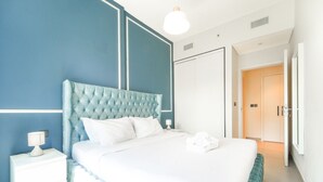 Quarto de hotel com uma cama grande, uma mesa de cabeceira, um abajur e um guarda-roupa.