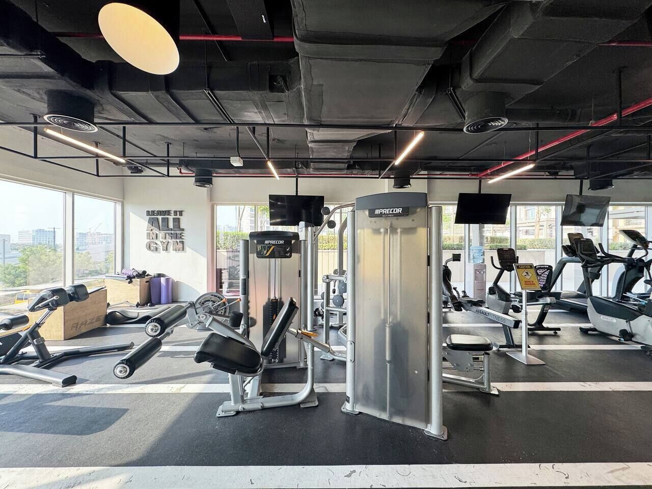 Een sportschool met diverse fitnessapparaten, waaronder een squatsysteem en loopbanden.