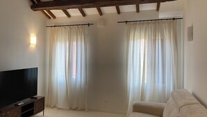 A living room with a flat-screen TV, a sofa, and sheer curtains. - Apartment with a view of the canal in a Venetian building (Venezia)