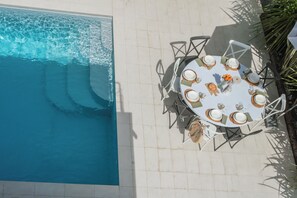 A poolside dining area with a round table, chairs, and a view of the pool. - Villa Chiara (Stresa)