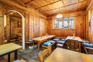 A wooden interior with a dining area, benches, and a chandelier.