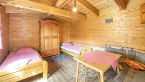 L’intérieur d’une cabane en bois comprend deux lits, une table, un banc et une armoire.