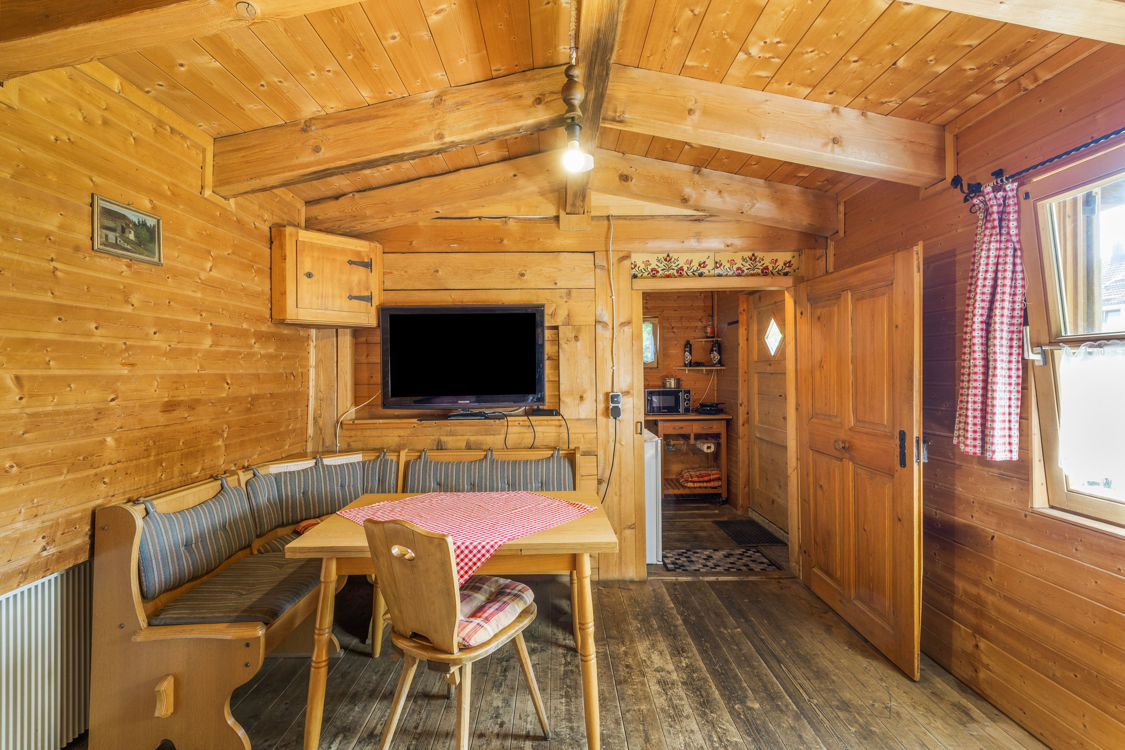 Ein Interieur einer Holzhütte mit Essbereich, Fernseher und Küche.