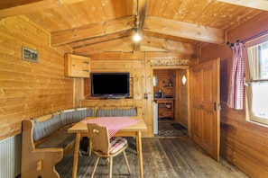 A wooden cabin interior with a dining area, a television, and a kitchen.