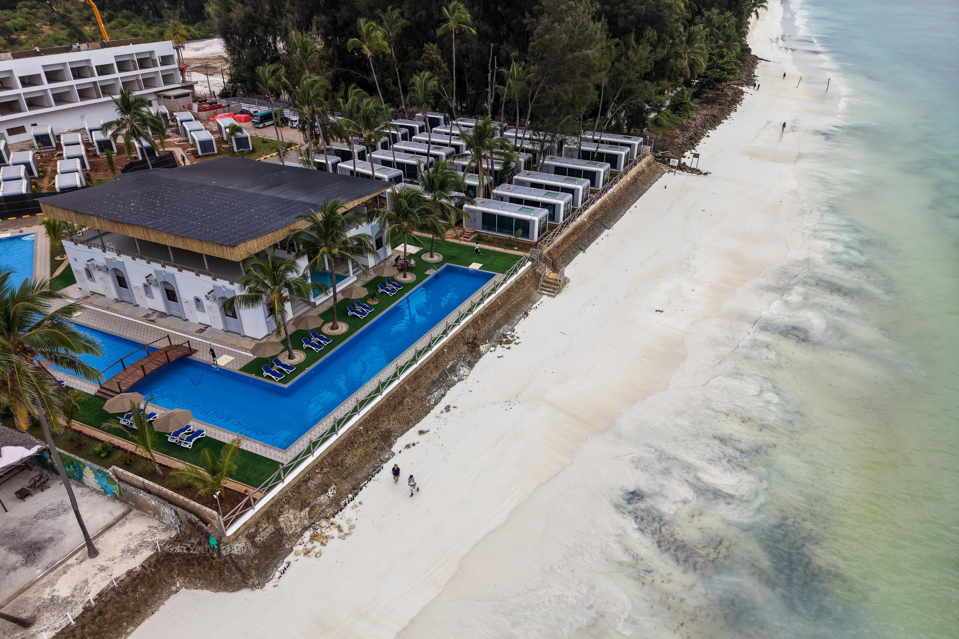 Vista aérea de un complejo turístico con piscina, playa y varias villas.