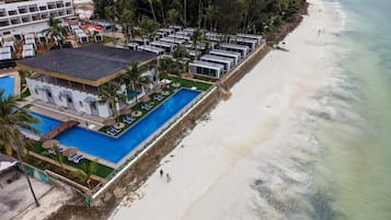 Vista aérea de un complejo turístico con piscina, playa y varias villas.
