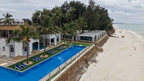 Un resort con piscina, sillones de descanso y playa.
