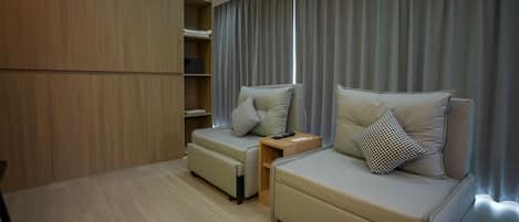 Un dormitorio moderno con un armario de madera, un sofá cama con una almohada, una mesita de noche y una ventana con cortinas.