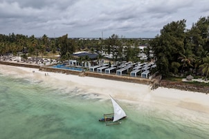 A coastal resort with a beach, a swimming pool, and several beachside structures.