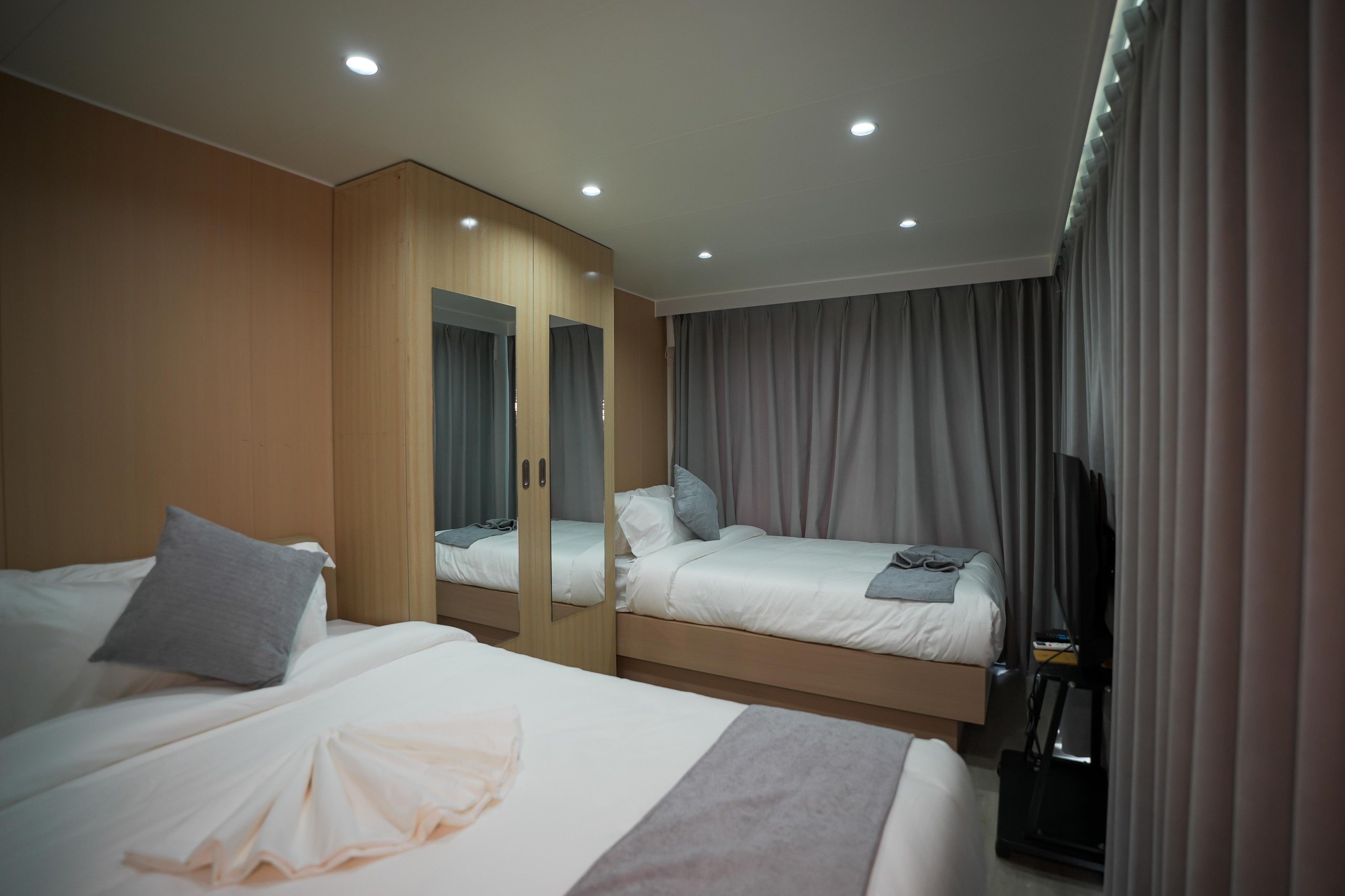 Habitación de hotel con dos camas, un armario, un televisor y una cinta de correr.