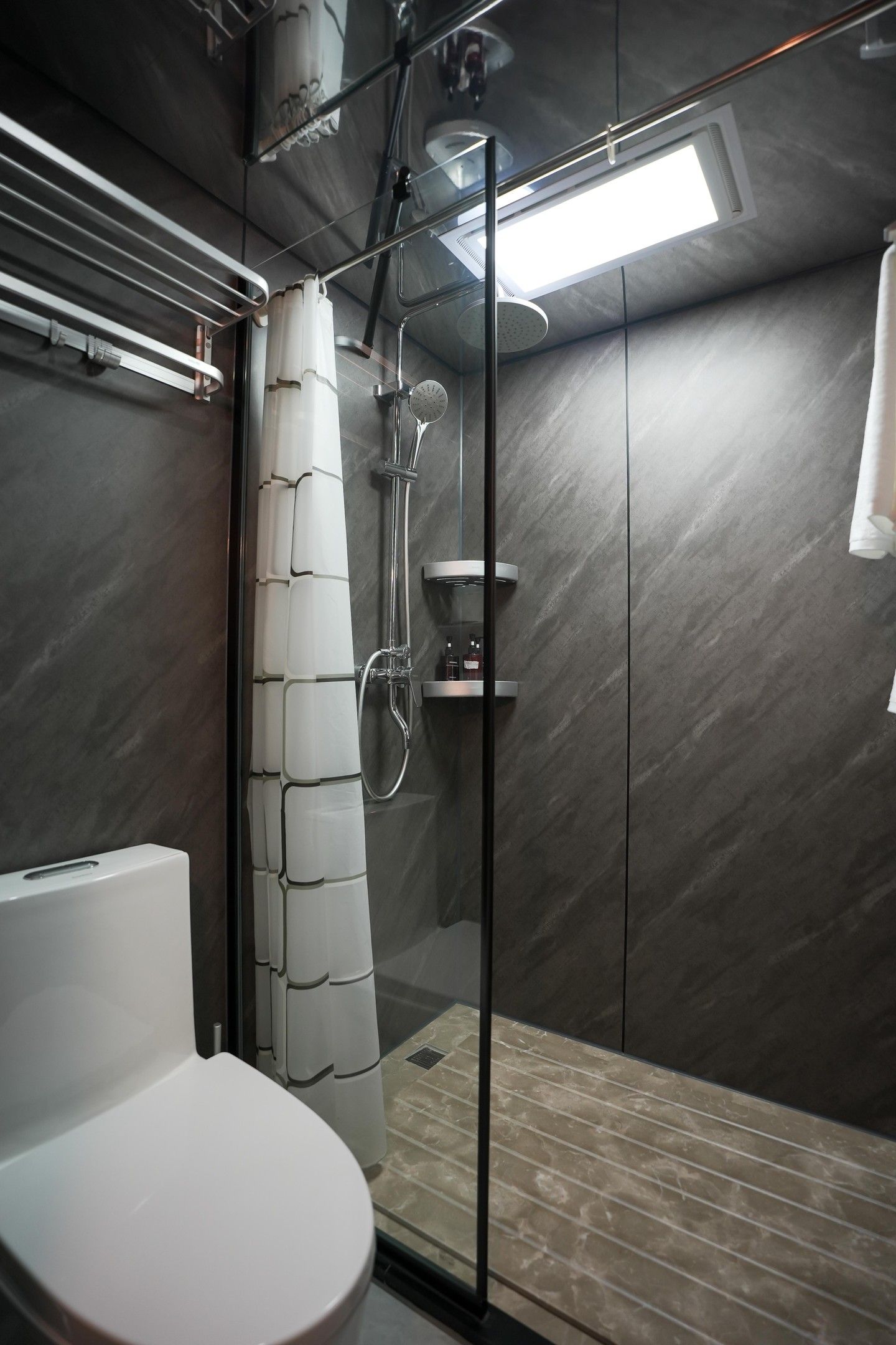 Ein modernes Badezimmer mit einer Glaskabine zur Dusche, einer Toilette und einer integrierten Ablage.