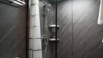 Ein modernes Badezimmer mit einer Glaskabine zur Dusche, einer Toilette und einer integrierten Ablage.