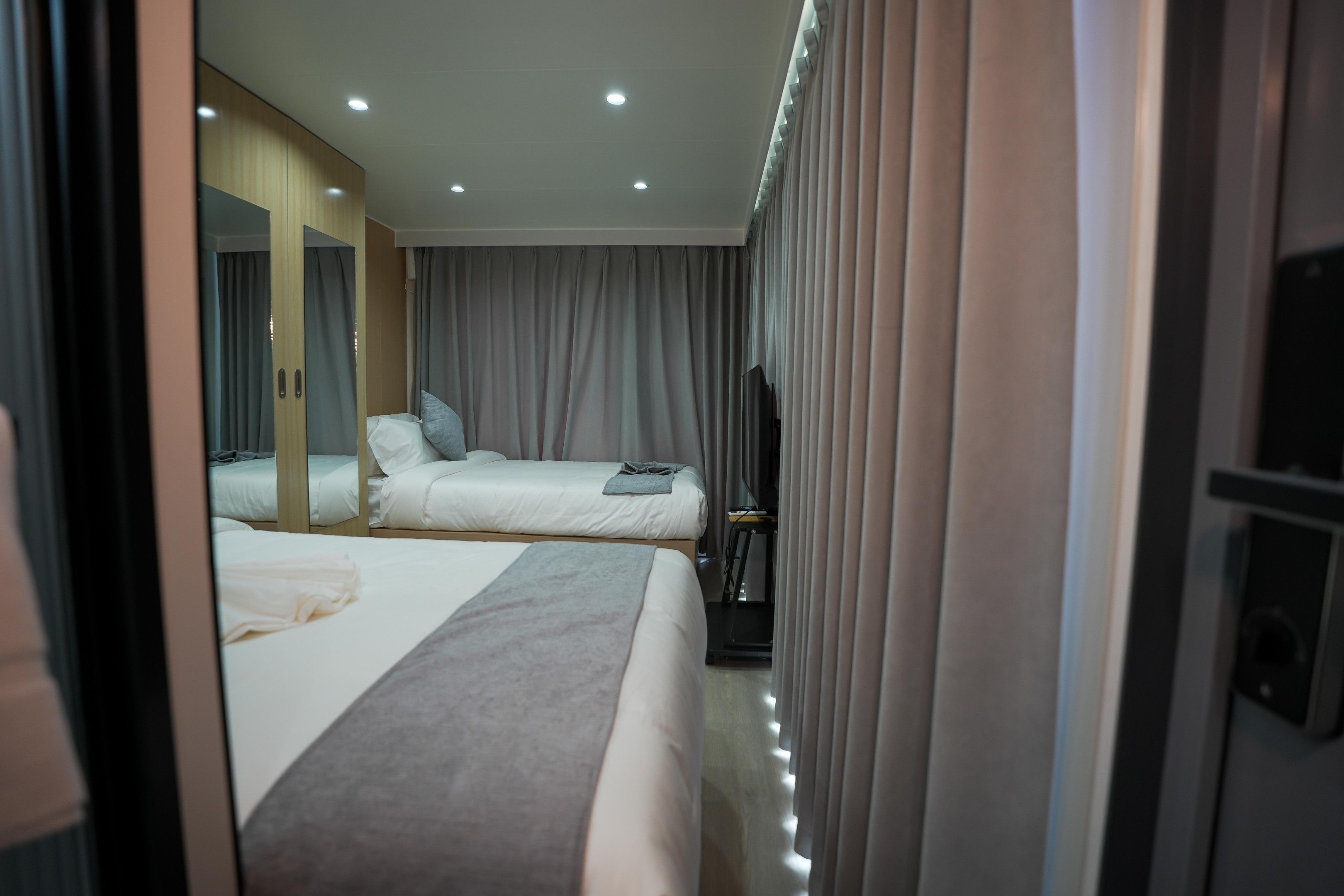 Ein Hotelzimmer mit zwei Betten, einem großen Spiegel, einem Laufband und einem Fernseher.