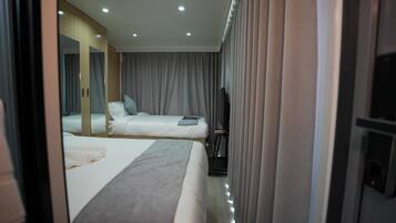 Ein Hotelzimmer mit zwei Betten, einem großen Spiegel, einem Laufband und einem Fernseher.