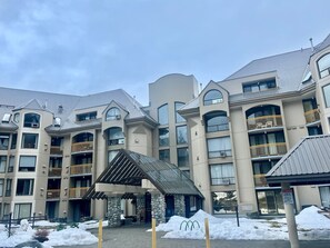 A multi-story hotel with balconies, a covered entrance, and snow on the ground. - Marquise Magic Mountain Escape. (Whistler)