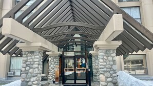 A hotel entrance with a stone facade, a glass door, and a covered entrance area. - Marquise Magic Mountain Escape. (Whistler)