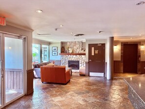 A spacious living area with a stone fireplace, a sofa, and a door leading to another room. - Whistler Serenity Sanctuary (Whistler)