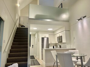A modern kitchen with white cabinets, a stainless steel refrigerator, and a glass dining table. - Whistler Serenity Sanctuary (Whistler)