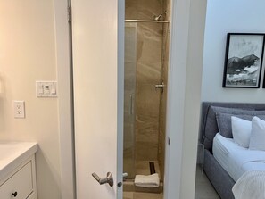 Habitació d'hotel amb dutxa, llit i un quadre a la paret.
