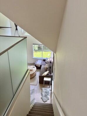 A staircase leading to a living area with a sofa, a small table, and a view of the outdoors. - Whistler Serenity Sanctuary (Whistler)