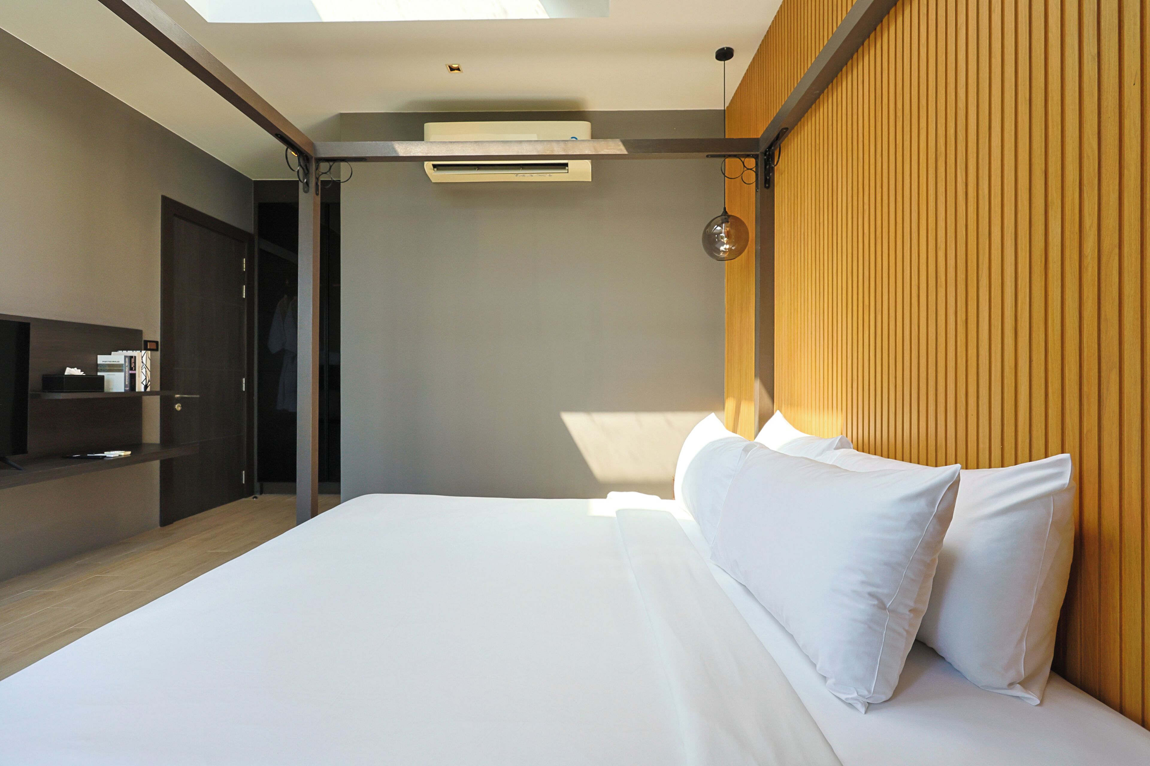 Een moderne hotelkamer met een groot bed, een ingebouwde televisie en een wand van hout.