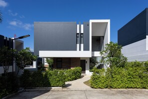 A modern two-story building with a flat roof, large windows, and a concrete pathway leading to the entrance. - Elite Suites Villas Maikhao Phuket (Thalang)