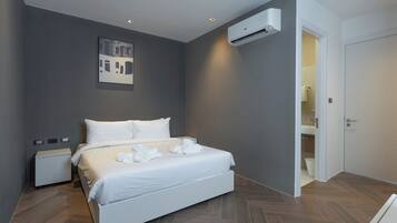 Een moderne hotelkamer met een groot bed, nachtkastje, airconditioning en een deur naar een badkamer.