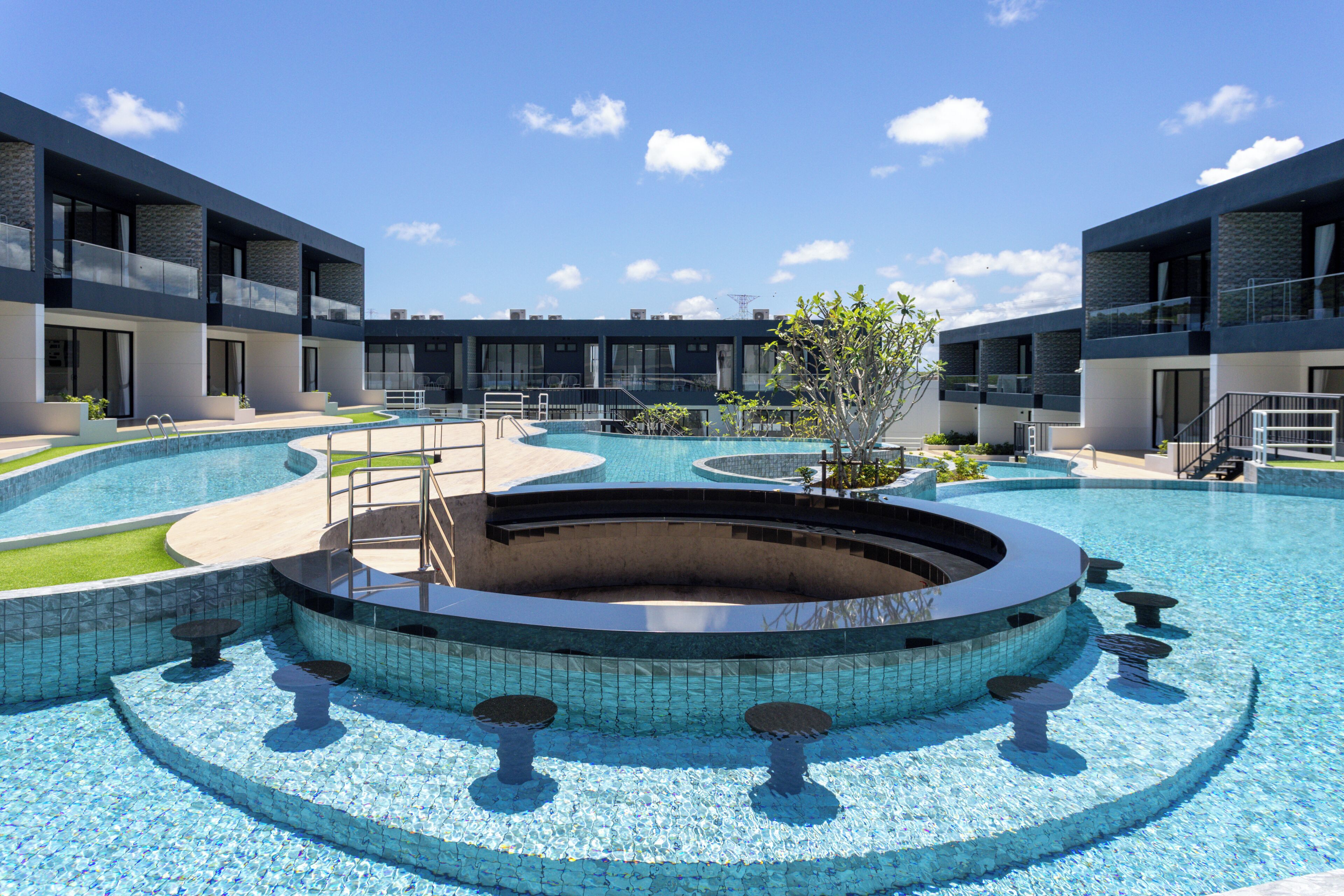 A modern pool area with a circular design, surrounded by multi-story buildings with balconies.