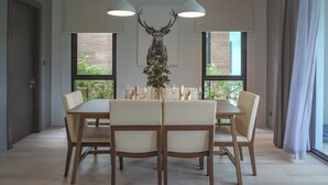 A dining area with a table set for four, two pendant lights, and a deer head decoration.