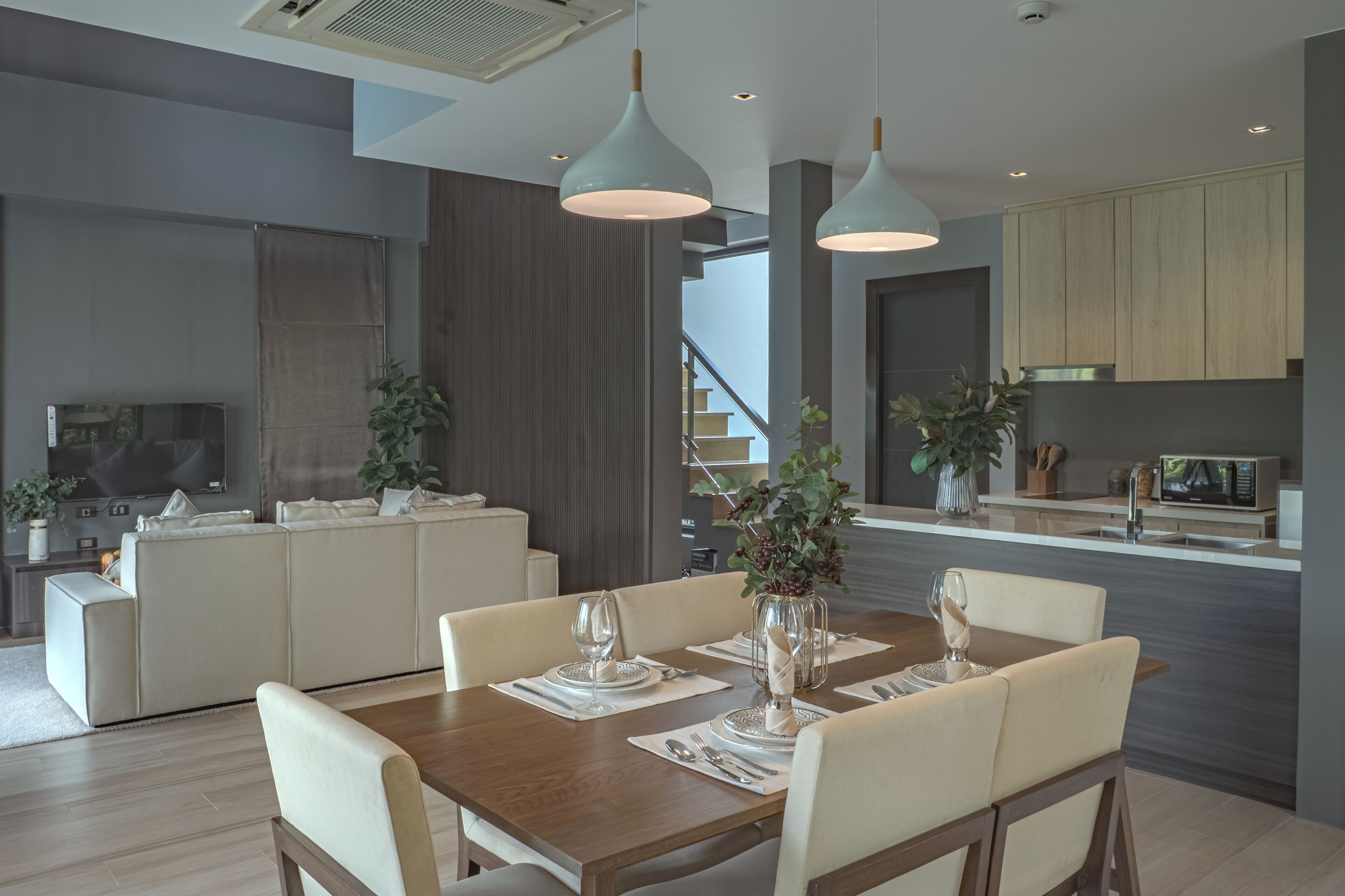 A modern dining area with a wooden table set for four, surrounded by cream-colored chairs.