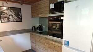 Una cocina compacta con microondas, horno y cafetera en la encimera.
