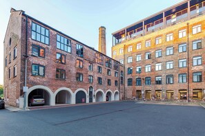 A multi-story building with a brick facade, large windows, and a parking area in front.